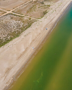 Aerial view of people with parasol on Plaja de Riumar, a beach in Delta de l'Ebre national park, Deltebre, Tarragona, Spain.