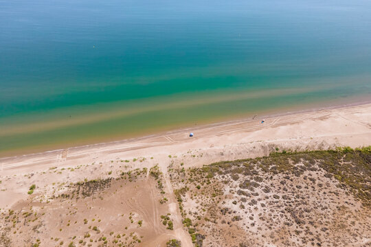 Aerial view of people with parasol on Plaja de Riumar, a beach in Delta de l'Ebre national park, Deltebre, Tarragona, Spain.