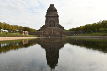 Fototapeta na wymiar Pond reflecting the Monument to the Battle of the Nations in Leipzig, Germany against a cloudy sky