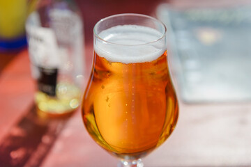 Glass of light beer on the wooden table.Glass of beer in nature.Empty bottle in a blurred background,summer day.