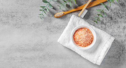 Himalaya salt in white bowl on towel with toothbrush on cement background, natural teeth and gum care