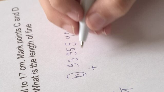 exercise in adding numbers, child, schoolchild hesitantly solves difficult task of adding numbers, student writes down numbers in notebook with pen, math lessons, education concept