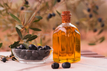 olive oil in a glass bottle and green olives on the background of olive branches in the garden