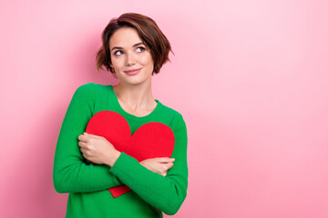 Photo of adorable dreamy lady wear green pullover embracing red heart looking empty space isolated...