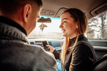 Young trendy couple discussing their route in the car with phones in hand - modern navigation at...