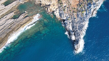 Aerial view of the unbridled energy and beauty of the sea The power of the foamy blue wave crashing against the sea rocks Turquoise sea from a bird's eye view