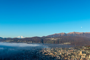 Snow-capped Mountain Peak Monte Rosa and the Moon Above Cloudscape and Lake Lugano with Sunlight...