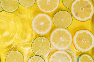 lemon and lime slices in water on yellow background