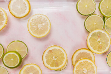 lemon and lime slices in water on pink marble background