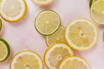 lemon and lime slices in water on pink marble background