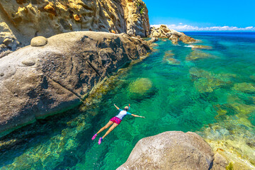 Top view of snorkeler in Sant 'Andrea beach Cote Piane side with rocks and coves, Elba island. Woman in clear waters of Tyrrhenian sea on holiday travel in Italy.Saint Andrew is popular seaside resort