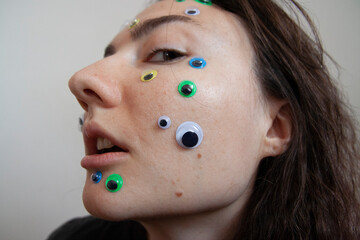 Young Ukrainian girl with white skin and dark hair with big eyes and stickers on her face emotionally depressed mental health issues portrait scared surprised emotions eyesight problems close-up skin 