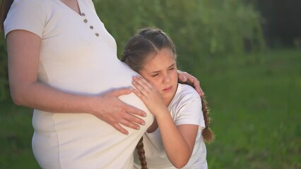 girl pregnant woman. daughter hugging her pregnant mother's belly. girl pregnant woman happy family kid dream concept. the girl loves her unborn brother,mother equally loves two children lifestyle