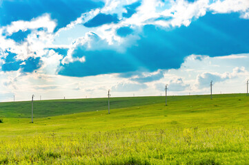 Green grassland under blue sky with white clouds and sunbeams