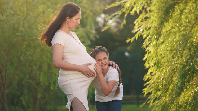 girl pregnant woman. daughter hugging her pregnant mother's belly. girl pregnant woman happy family kid dream concept. the girl loves her unborn lifestyle brother, mother equally loves two children