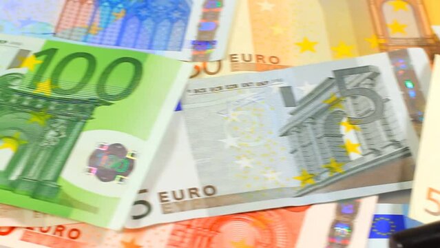 Camera pans to magnifying loupe over money. Euro paper notes passing in front of camera. Perfect for any financial, commerce, treasury or banking video needs.
