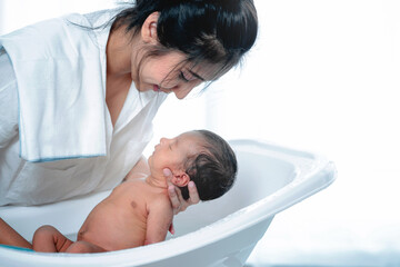 Asian mother take care her newborn baby, bathing in bathtub, adorable newborn infant still sleep,...