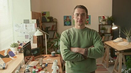 Medium portrait of talented sneaker designer standing in loft studio with plants, paintings and desk looking at camera at daytime