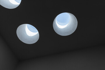Round ceiling skylight portals with blue sky behind in a dark room