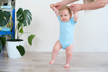 Baby taking first steps with mother help at home. child is learning to walk