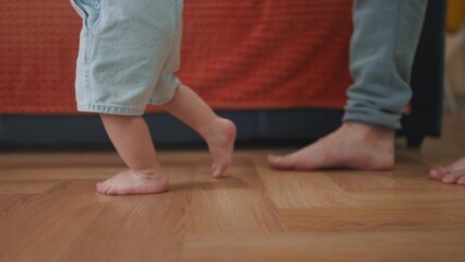 baby first steps. daddy a teaches baby toddler son to take first steps. happy family kid dream concept. baby indoors learning to walk father holding child hands. lifestyle fathers day concept