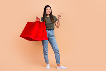 Full body photo of shopaholic fashionista model korean girl direct finger empty space red bargains pull bear isolated on beige background