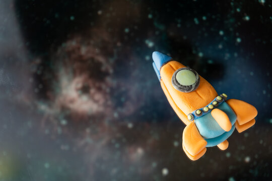 A spaceship made of plasticine in space, children's creativity, fantasies. Bright and cosmic background for the website and postcards for Cosmonautics Day. - Powered by Adobe
