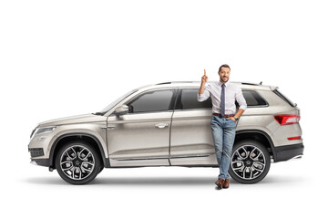 Full length portrait of a man leaning on a SUV and pointing up