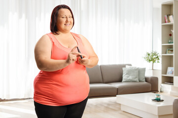 Overweight young woman poking finger with a medical device at home