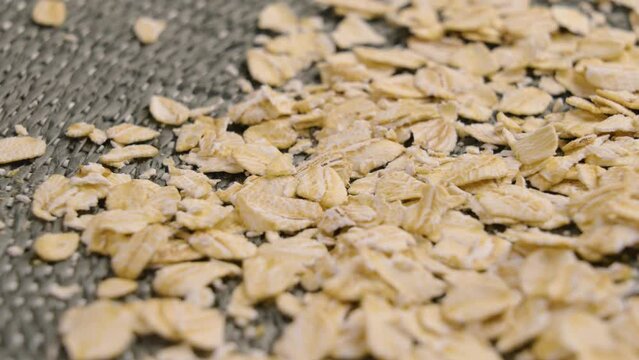 Uncooked rolled oat flakes for oatmeal porridge on a wicker surface. Macro. Rotation. Healthy eating concept
