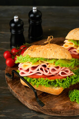 Sandwich. Tasty sandwich with ham or bacon, cheese, tomatoes, lettuce and grain bread on dark backgrounds. Delicious club sandwich or school lunch, breakfast or snack.
