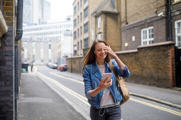 Young woman using a phone while walking in the city london