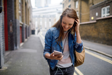 Young woman using a phone while walking in the city london - obrazy, fototapety, plakaty
