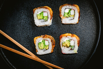 photography of japanese sushi roll, chopsticks on blue plate on black table, asian food, delicious japanese sushi