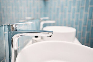 Two sinks in the bathroom sink next to stylish decorations. A beautiful sink with a metal faucet next to an mirror and a shelf with hand towels.. 