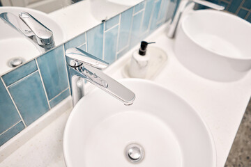 Two sinks in the bathroom sink next to stylish decorations. A beautiful sink with a metal faucet next to an mirror and a shelf with hand towels.. 