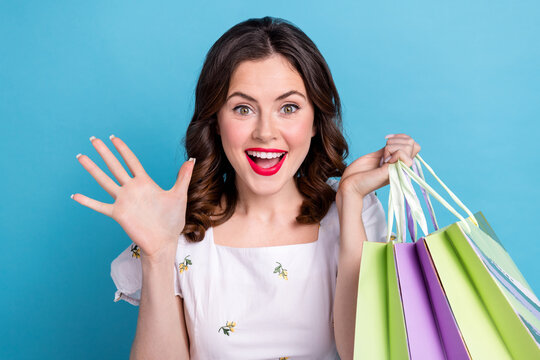Photo portrait of pretty girl pouted hold shopping bags wave hand excited dressed stylish blue outfit isolated on pink color background