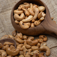 Roasted cashew nuts and halves in wooden bowl on table top view. Macro studio shot Homemade Roasted Salted Cashews in basket and spoon breakfast on sack, Healthy food Seeds snack product