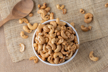 Roasted cashew nuts and halves in wooden bowl on table top view. Macro studio shot Homemade Roasted Salted Cashews in basket and spoon breakfast on sack, Healthy food Seeds snack product