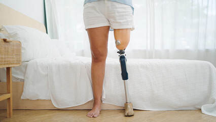 Close up leg prosthetic equipment of amputee standing at bedroom. Difficulties in disabled people...