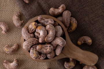 Roasted cashew nuts and halves in wooden bowl on table top view. Macro studio shot Homemade Roasted Salted Cashews in basket and spoon breakfast on sack, Healthy food Seeds snack product