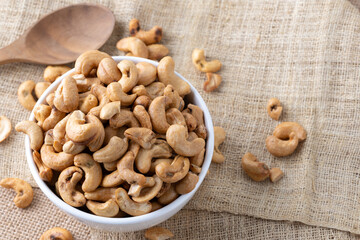 Roasted cashew nuts and halves in wooden bowl on table top view. Macro studio shot Homemade Roasted...