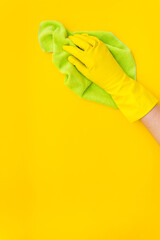 Female cleaner hand in yellow glove cleaning surface with duster