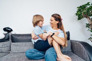 Overjoyed young mother having fun with her kid at home, laughing happy mum, adorable son playing...