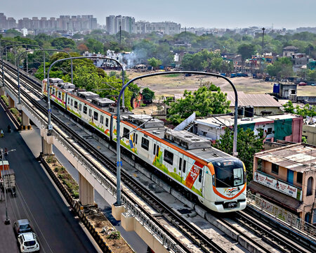 Nagpur, Maharashtra, India-April 20th, 2022: Metro train of orange line route in Nagpur passing on elevated track with blue sky background.