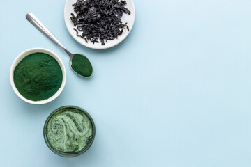 Fototapeta na wymiar Spirulina algae powder in bowl and cold milk latte drink, top view