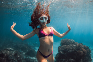 Attractive woman with mask underwater. Freediving or snorkeling in transparent blue ocean