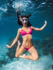 Obraz na płótnie Canvas Young woman in bikini fun underwater in transparent ocean.