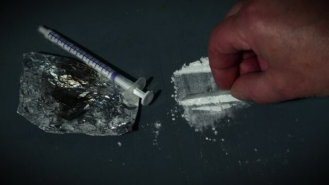 Drug addict preparing lines of heroin for injection