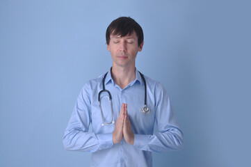 médico clínico fazendo oração com estetoscópio em fundo azul, fé e medicina